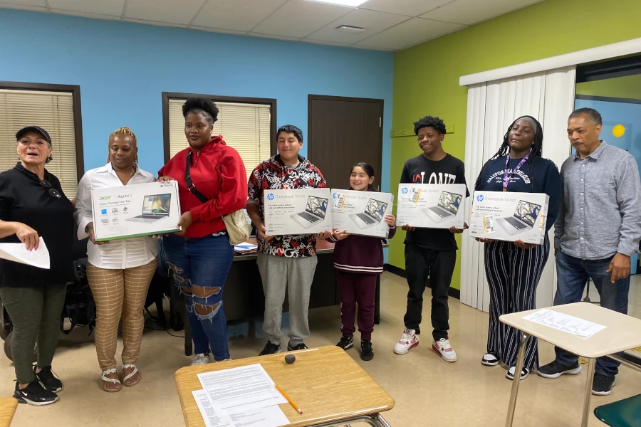 Group of young adults holding laptop boxes